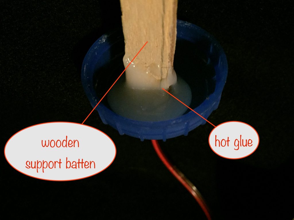 a photo of the underside of the milk container lid showing how the wooden batten is hot-glued to it 